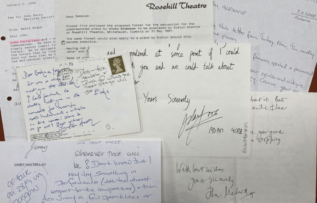 An image showing a collection of handwritten and typed letters, postcards, and notes arranged on a surface. The correspondence includes both personal and professional messages, with visible names such as James MacMillan and Rosehill Theatre. Some letters are typed on letterhead, while others are handwritten in blue ink. The materials vary in size and format, reflecting decades of communication between Dame Evelyn Glennie and composers around the world.